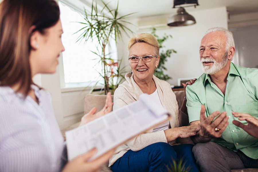 Contact - An Agent is Talking With an Older Couple About Life Insurance at Their Home