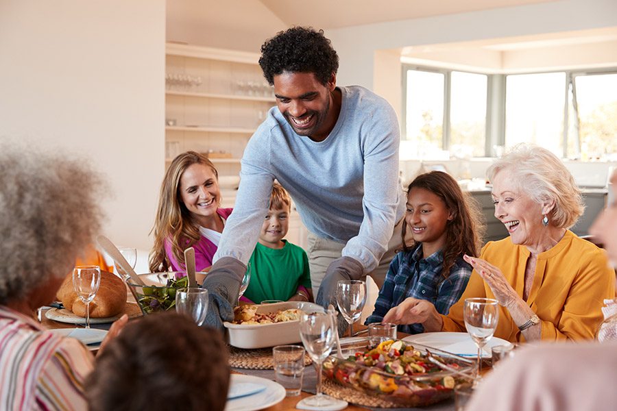 Personal Insurance - A Large Family is Enjoying Dinner While a Father is Setting a Main Dish on the Tablet at Home